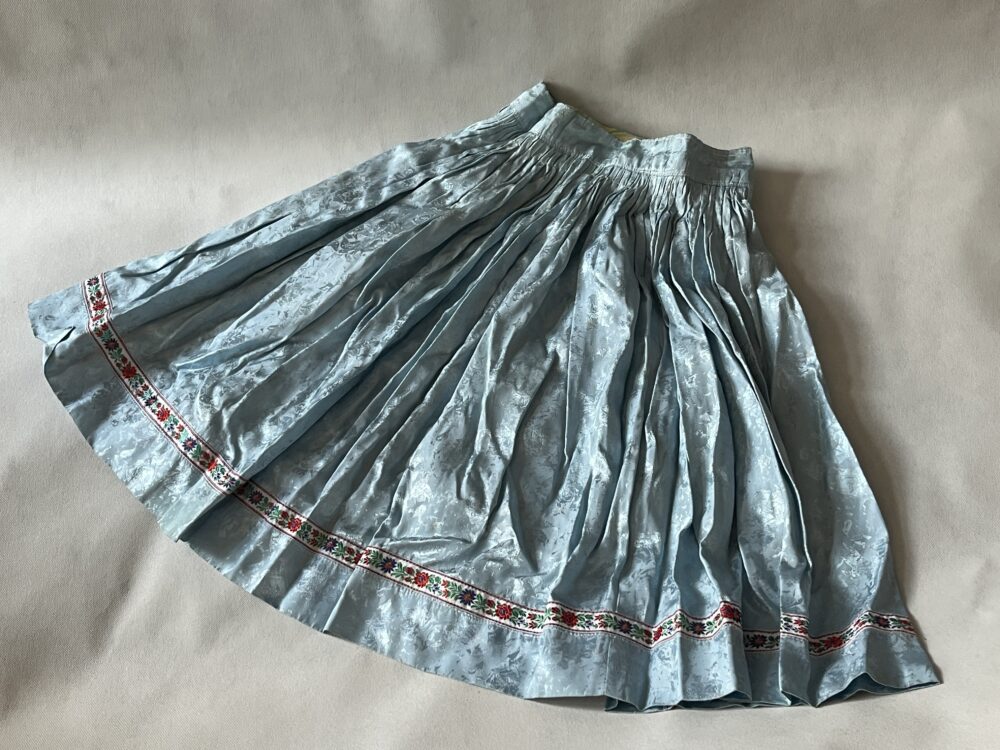 Součást lidového kroje Sukně brokátová světle modrá s vyšívanou stuhou