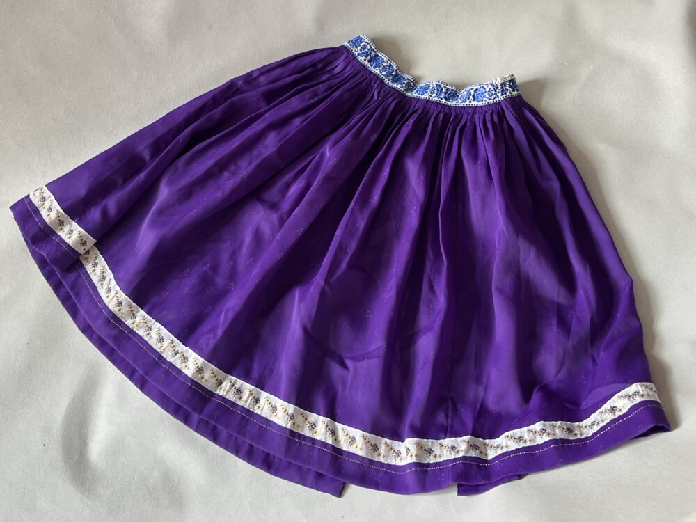 Součást lidového kroje - Sukně fialová s vyšívanou stuhou