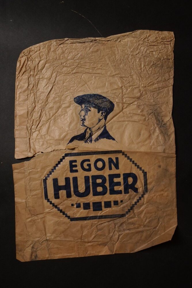 Reklamní sáček Egon Huber,obchod s klobouky,čepicemi 1.pol.20.st.